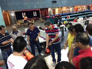 Coach Kevin Lee showing parents the correct way to hold the bowling ball.