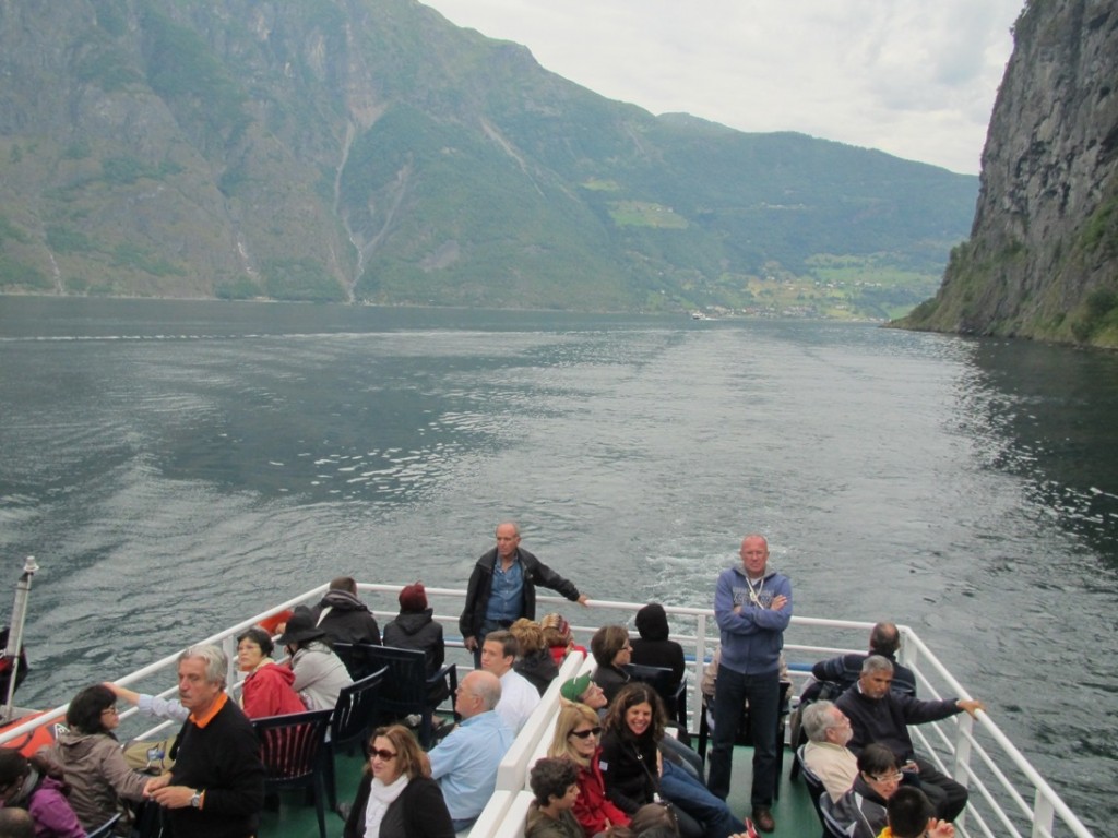 On the open deck of the boat, cruising down the fjord