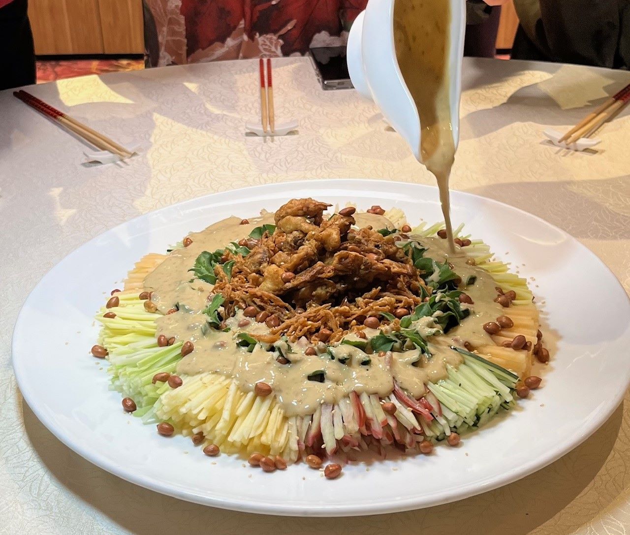 Drizzling the sauce on the Softshell crab, crispy enoki, fruits and ...